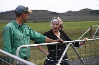A woman talking to a man on a farm.